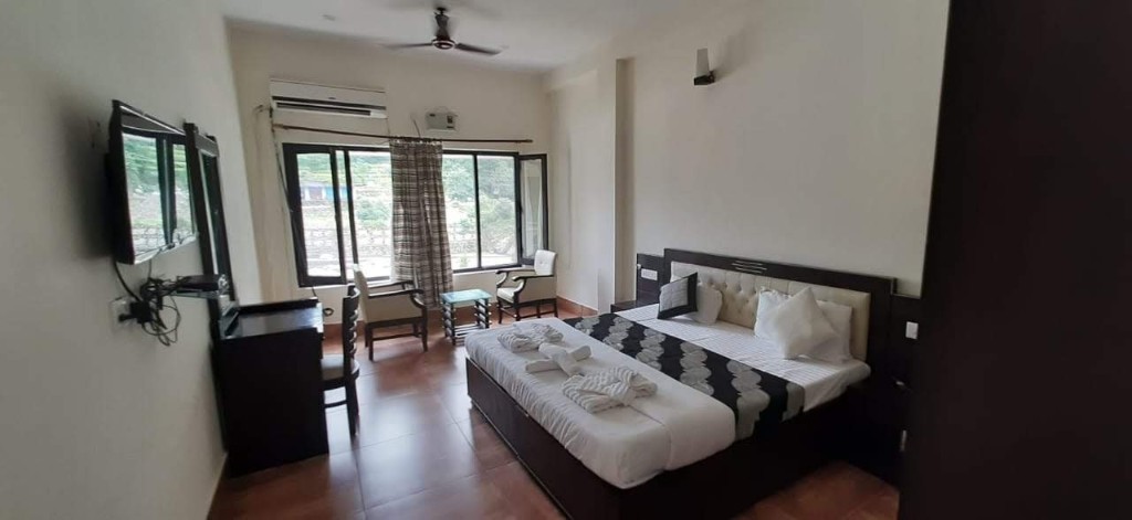 Deluxe double room with king bed, window seating, and mountain view at Shiv Parivar Resorts