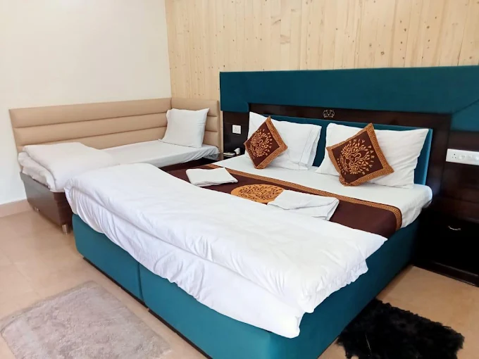 Triple bed family room with teal accents at Shiv Parivar Resorts