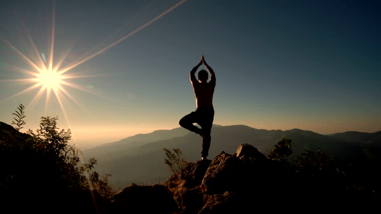 Silhouette in tree pose on a summit at sunrise — yoga and mountain calm at Shiv Parivar Resort